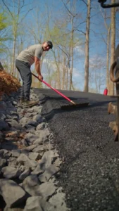 asphalty paving crew pressing sides of road paving for durability